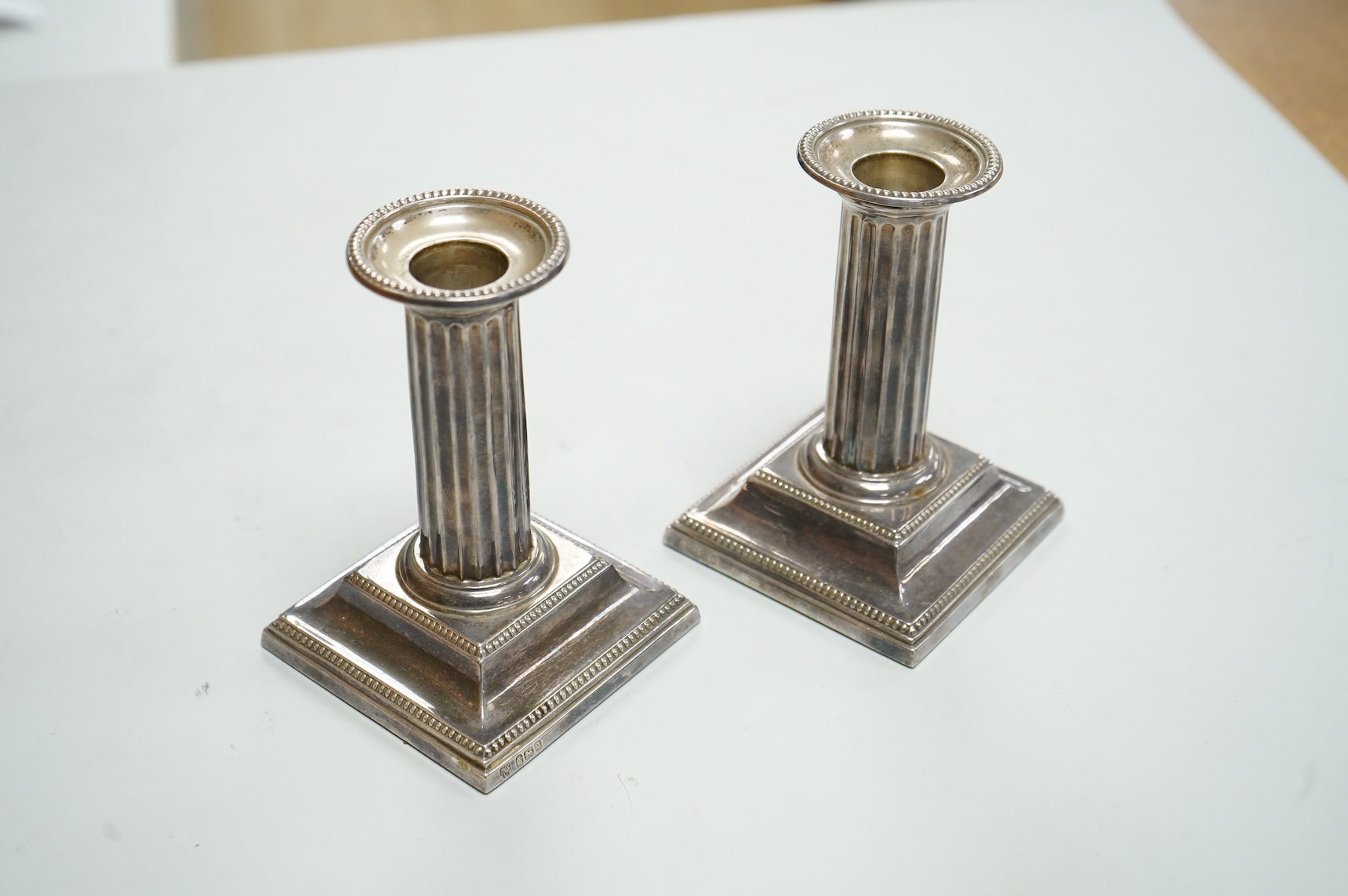 A pair of Edwardian silver mounted fluted column candlesticks, by Hawksworth, Eyre & Co, Sheffield, 1905/6, height 12cm, weighted.